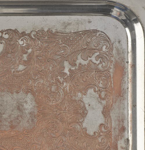 Detailed view of silver layer loss from a silver-plated copper tray.
