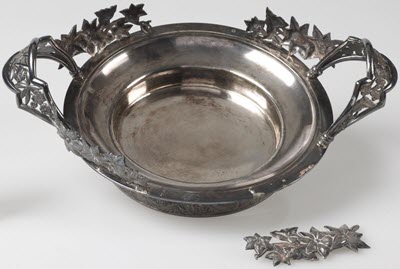 An ornamental piece of foliage broken off of a decorative silver bowl.