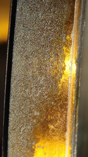 Detail of corrosion on the mirror rim of a lacquered brass microscope.