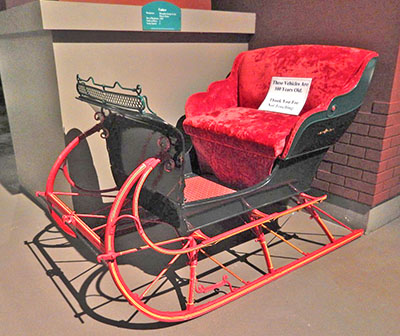 There is a sign on a sleigh and it states: These vehicles are 100 years old. Thank you for not touching.