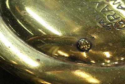 Detail of scratches and corrosion on a Gray & Davis brand brass headlamp on the Le Roy automobile.