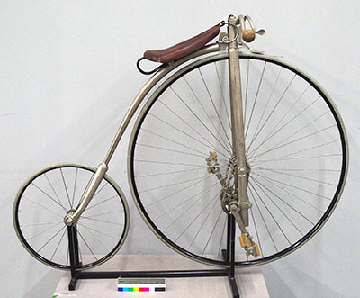 A sturdy, custom-made metal stand for an 1886 high-wheeler bicycle.