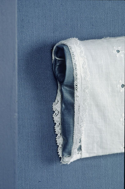 Detail of one of the sleeves of a christening gown suspended on a dowel.