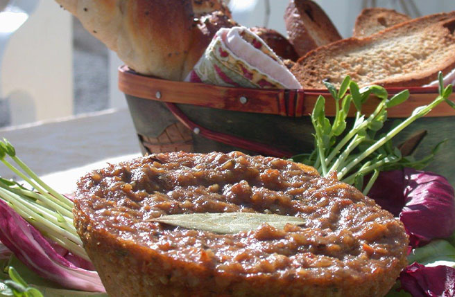 Gros plan d’un végépâté tartiné, présenté avec des tranches de pain et des légumes frais.