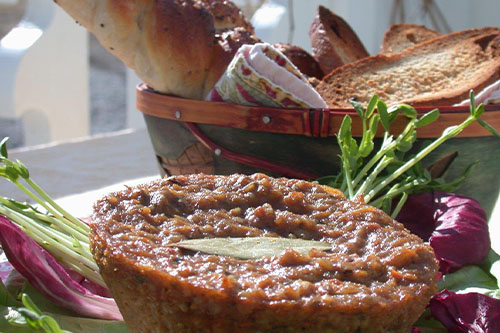Gros plan d’un végépâté tartiné, présenté avec des tranches de pain et des légumes frais.