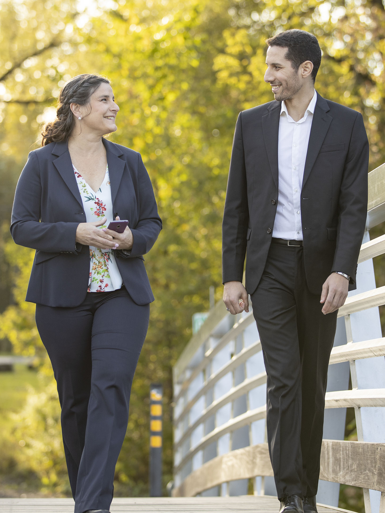 Pasquale Beauvais et Lahbib Aissaoui, copropriétaires de Bio-Bon, marchant et discutant sur un pont piétonnier dans un parc.