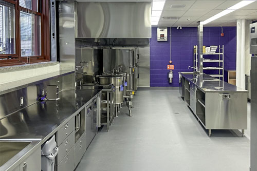 Cuisine en acier inoxydable avec comptoirs et équipements professionnels.