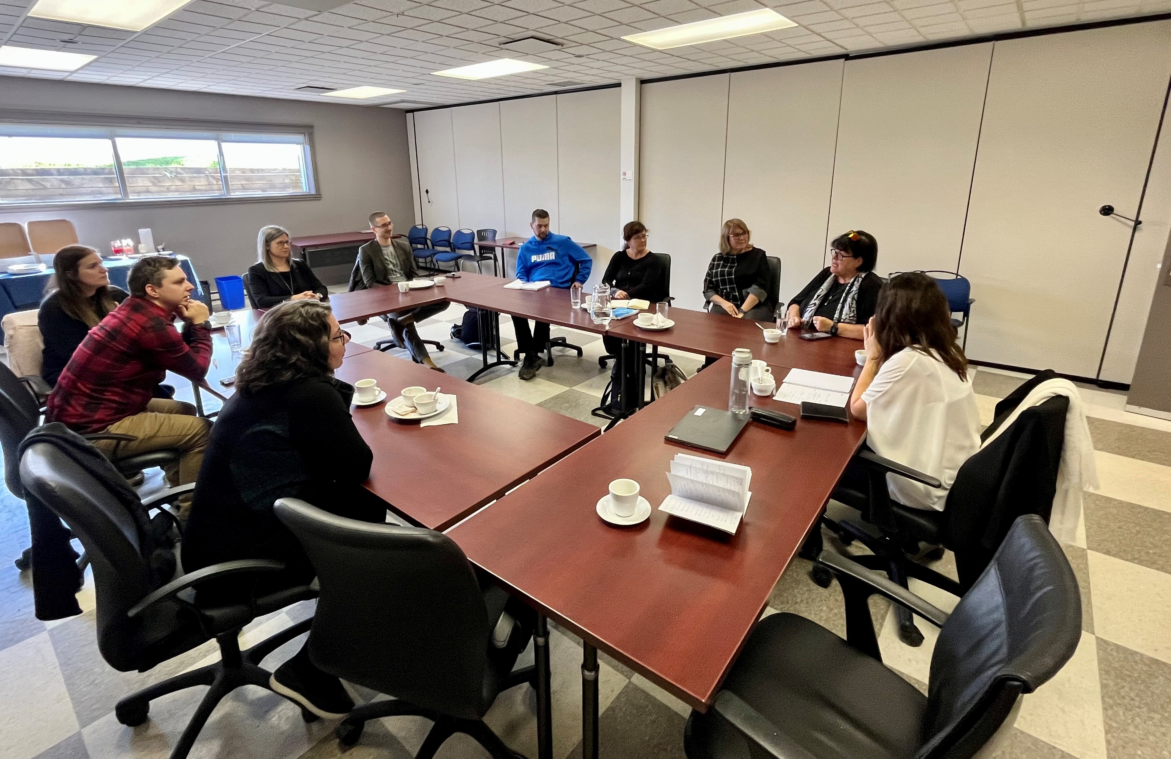 A dozen people are gathered around a table for a lively discussion. A dozen people are gathered around a table for a lively discussion.