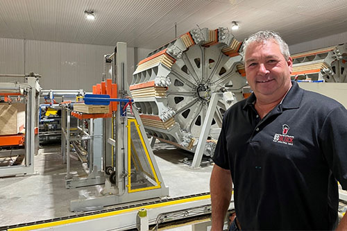Marco Tremblay smiling inside the OSBLOCK plant, standing in front of automated production machinery