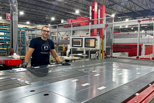 Un employé pose avec une plieuse automatisée dans l’usine.
