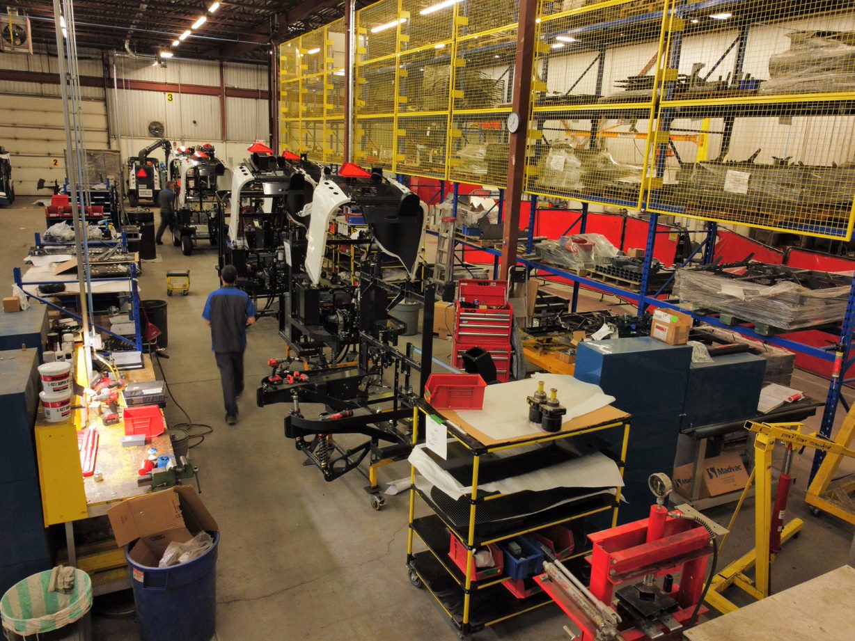 Dans l’usine d’Exprolink, un employé marche le long d’une rangée de véhicules électriques en cours d’assemblage.