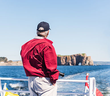 Two tourists on a cruise on a windy day; the Rocher Percé can be seen in the background