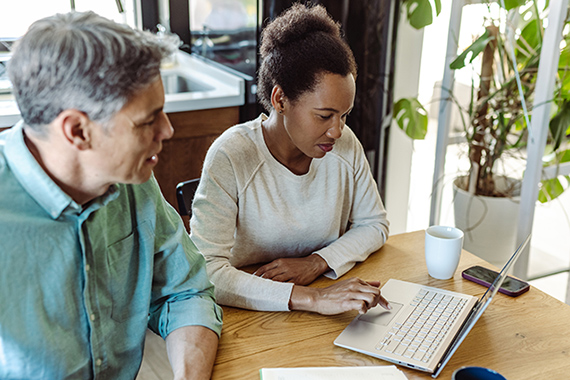 Multi-racial mature couple calculating costs at home at the table. They discussing home finances.