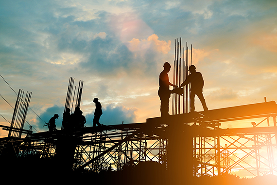 Silhouette d'un ingénieur et d'une équipe de construction travaillant sur un chantier sur fond de coucher de soleil
