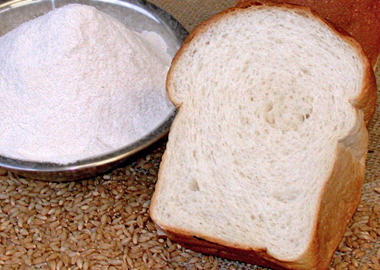 A loaf of bread made with barley fibre fractions, a bowl of fibre fractions and barley grains.