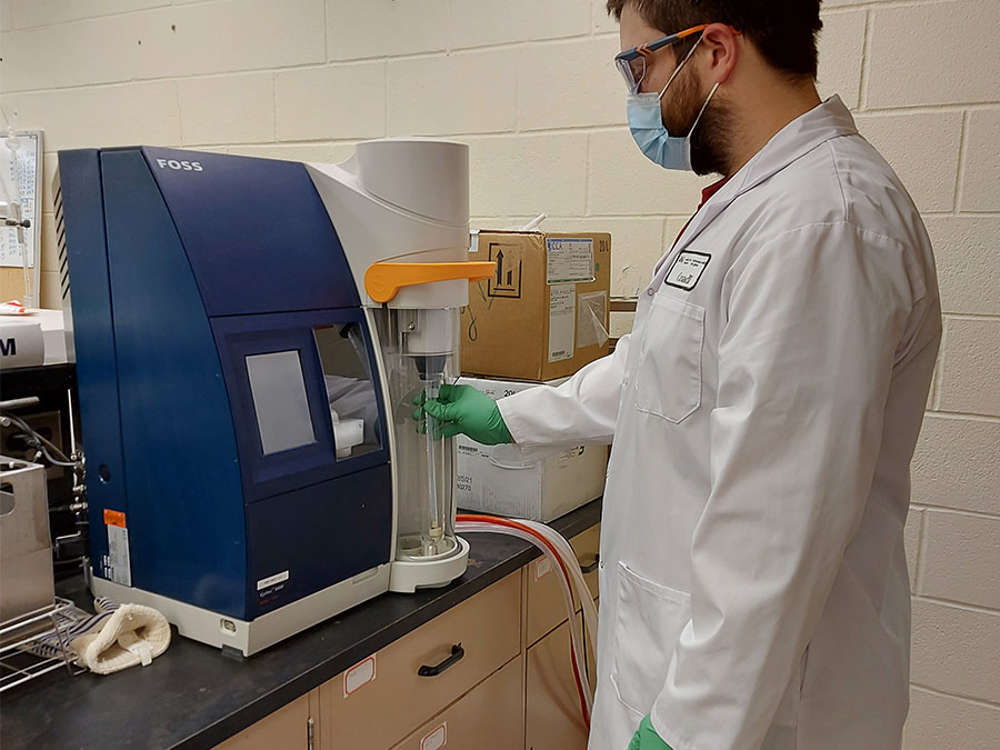 Lab technician operating Kjeldahl analysis equipment.