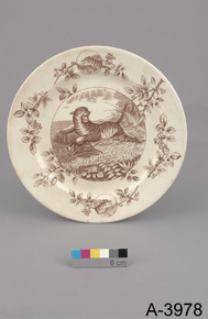 Colour photo of ceramic plate with floral decorative pattern and the image of a tiger, with catalogue number A-3978 on a grey background.
