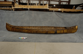 Initial view of a wooden canoe with partial neutral background.
