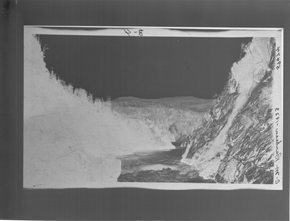 Black and white photograph of mountainous river landscape, showing original negative colours.