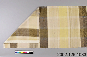 Colour photo of a rectangular piece of patterned fabric, folded to show both sides, with catalogue number 2002.125.1083 on a grey background.