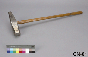 Colour photo of steel sledgehammer with wooden handle with a colour scale and CN-81