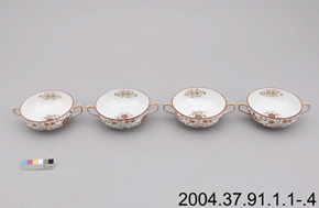 Colour photo of four patterned tea-cups with double handles and floral designs with a colour scale and 2004.37.91.1.1-.4