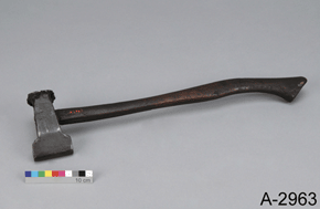 Colour photo of a metal hammer-like tool of black colour with a long handle with scale and the text A-2963