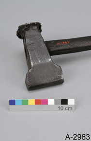 Colour photo of a metal hammer-like tool  with 10 cm scale and the text A-2963
