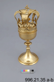 Colour photo of golden goblet with ornate crown decorative top, includes a 6cm colour scale and 996.21.35 a-b