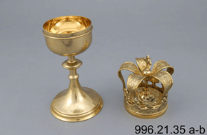 Colour photo of golden goblet with ornate crown decoration by its side and 996.21.35 a-b