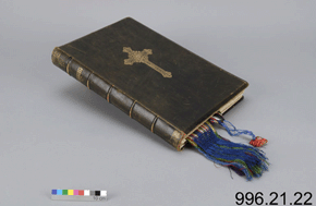 Colour photo of a black leather book with a cross design on the cover with a scale and the number 996.21.22