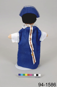 Reverse view of hand-puppet, showing the back of its blue, red, and white colonial-era costume with a colour scale and the number 94-1586