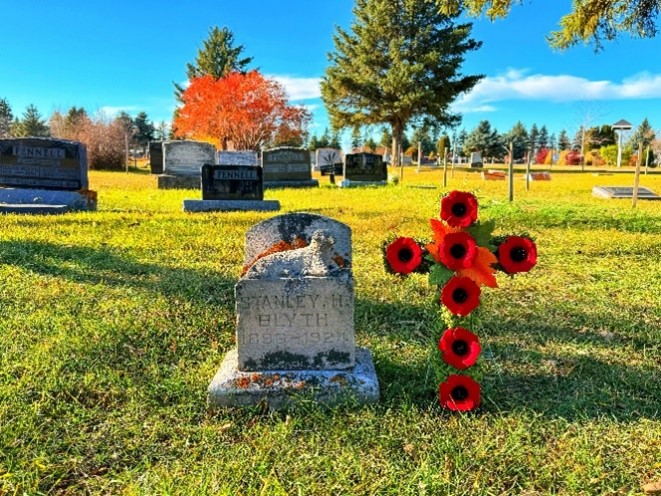 Une croix du Souvenir placée à côté d’une tombe.