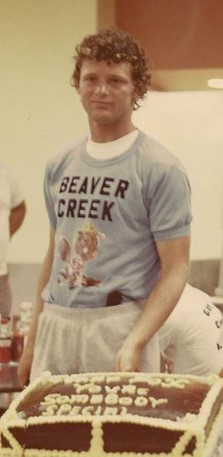 Terry Fox porte un gilet de l’Établissement de Beaver Creek et se tient devant un gâteau.