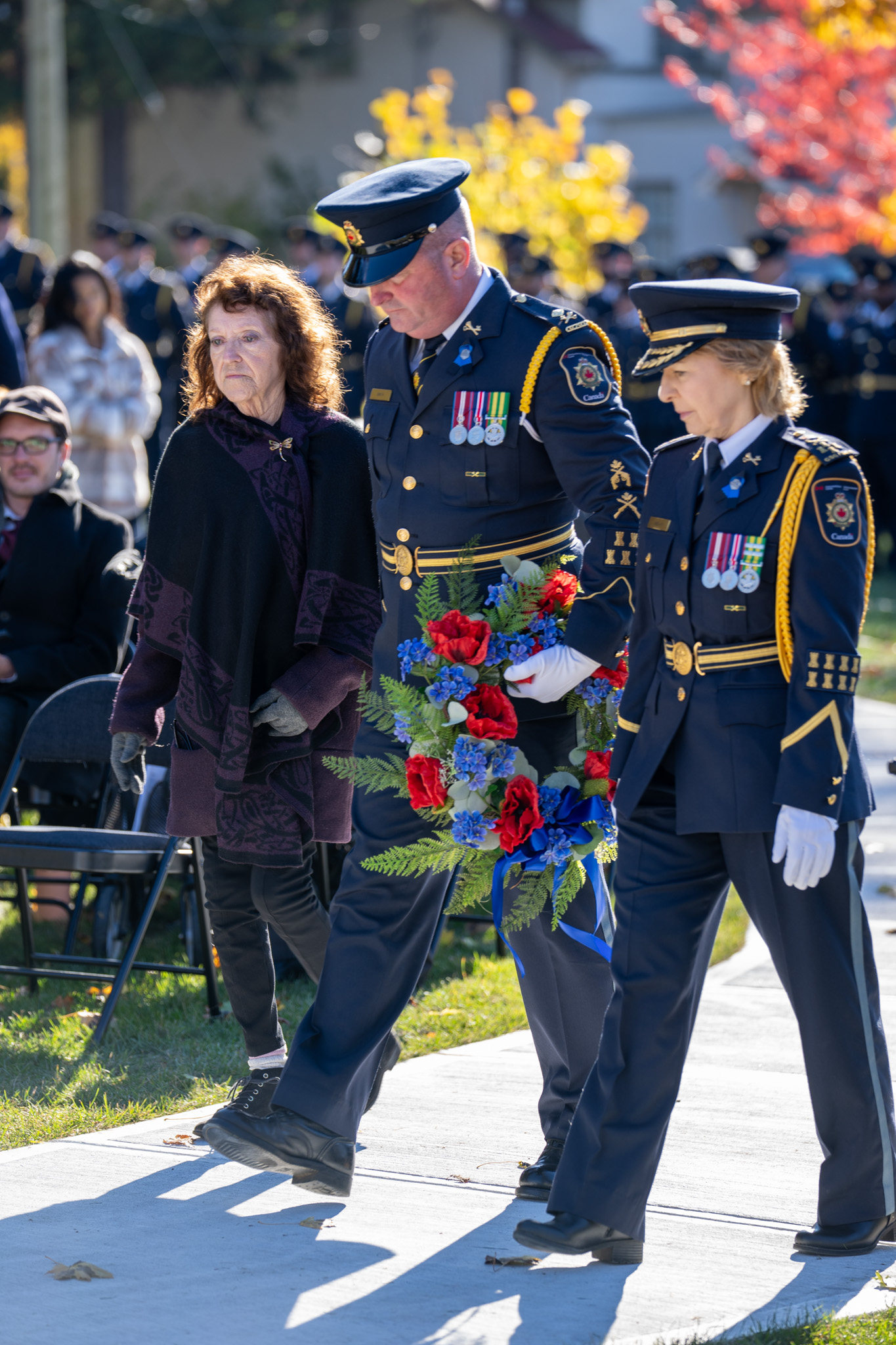 Daphne Jenkins walking with Correctional Manager Matt Smith and Commissioner Anne Kelly in their uniforms. Matt is holding a wreath.