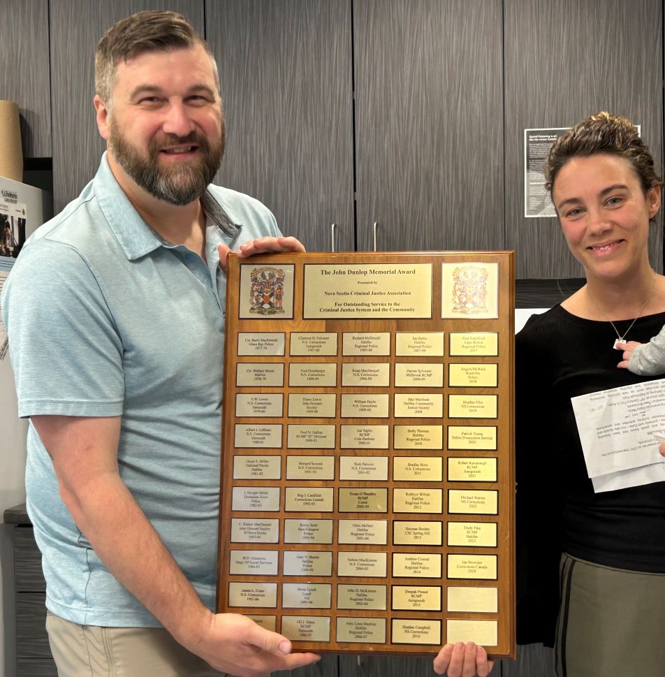 Ian Brewster tenant la plaque des lauréats du Prix commémoratif John Dunlop.