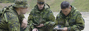 3 military personnel looking at a document in the field