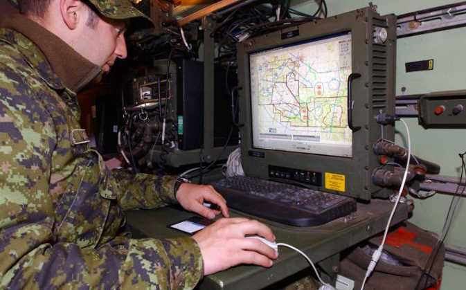Picture shows an army personelle looking at a screen with a map