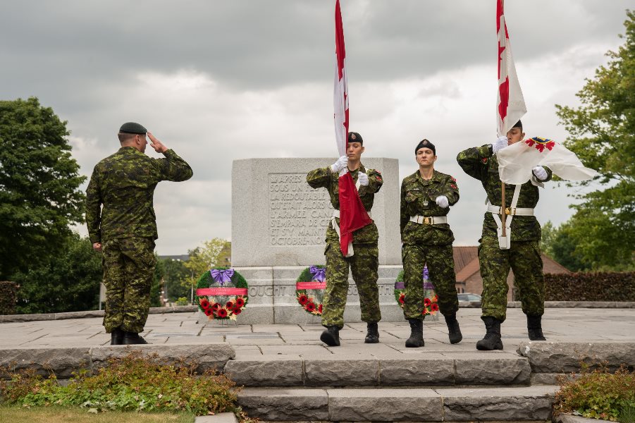 Military personnel standing in front of a memorial.
