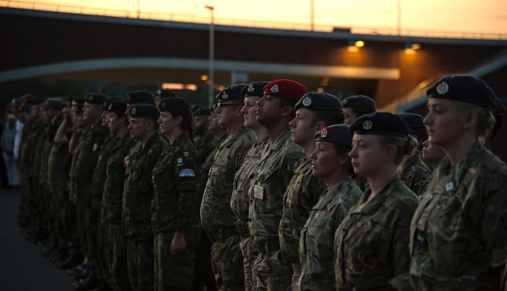 Military personnel standing in a group at sunset.