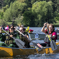 Participants of the canoe launch with their decorated canoes and costumes; a banana split boat, a flowered boat, and an alligator boat.