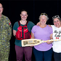 LGen Kelsey presenting the award of best decorated canoe to Lcol Kirsten Mathisen, Capt Katherine Quint and Tanya Morin, also known as team This Ship  Is B-A-N-A-N-A-S with a banana split canoe.