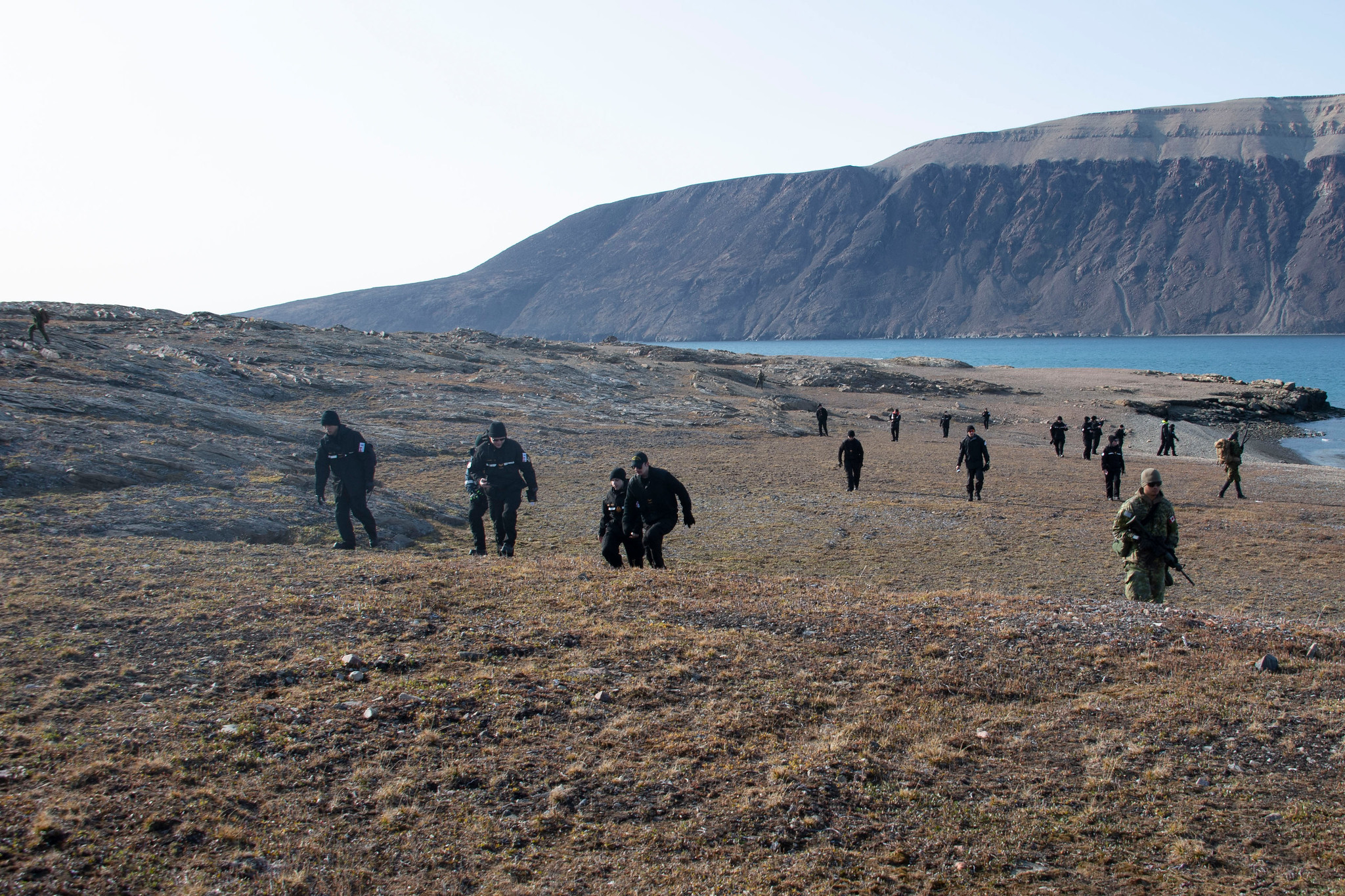 Des membres d’équipage du NCSM HARRY DEWOLF et des escortes de la Force opérationnelle terrestre parcourent le terrain accident de l’île Devon au cours de l’opération NANOOK-NUNAKPUT, le 21 août 2021.