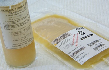 A glass bottle and a plastic IV bag that both contain a yellow liquid. The glass bottle has a label dated 1943 and the IV bag label is dated 2019.