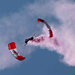 Empilage à trois avec traînée – Vous voyez très bien, le troisième parachutiste de cette manœuvre a la tête complètement suspendue! Cette formation intitulée «Empilage à trois avec traînée» doit maintenir une vitesse avant considérable pour s’assurer que la voilure à l’envers demeure gonflée!