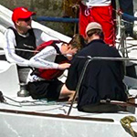 Members of the 2023 RMC Varsity Club Sailing Team preparing for a practice (from L to R): NCdt Mikhael Zavala Thyer (black jacket and red PFD), NCdt Jamie De Lachevrotière-Martin (red hat inside the companionway), OCdt Willem Quist (standing white shirt and red short), NCdt Justin Norman (sitting over the cockpit to see what Rodriguo is showing), (Rodriguo sitting with black jacket, Chilean in charge of the regatta and teaching how to do something), and OCdt Spencer Talerico (standing on the right of the Canadian flag).