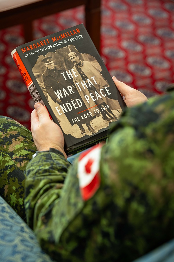 Un soldat en tenue de camouflage tient un livre à couverture cartonnée.