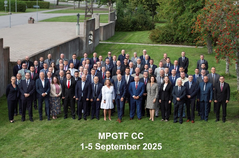 High-angle group photo of formally dressed participants standing on a grassy lawn in front of a historic building with text MPGTF CC 1-5 September 2025 on the photo.