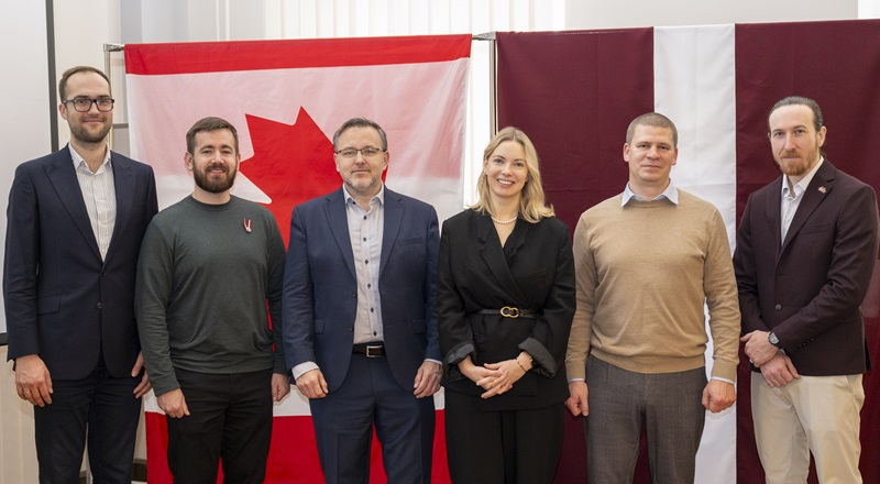 Group photo of Canadian and Latvian representatives, including the Canadian Ambassador and Latvian Ministry of Defence official at the centre, standing in front of Canadian and Latvian flags with CyTF 2 and CERT.LV personnel.
