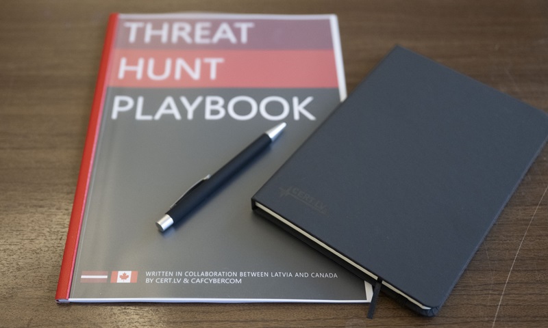 Close-up of the Threat Hunt Playbook with a pen and a CERT.LV notebook on a table, showing the collaboration between Latvia and Canada.